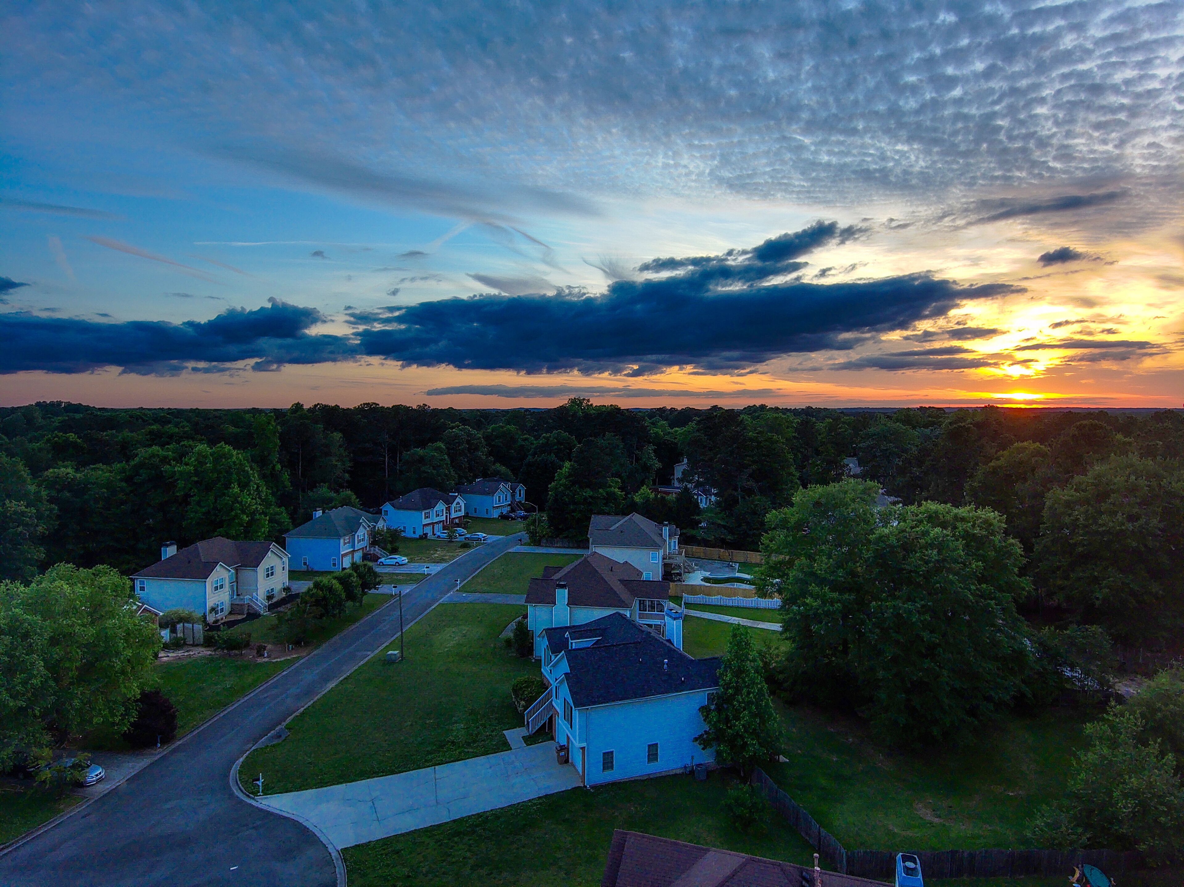 a breathtaking aerial shot of a sunset over Powder Springs Georgia with miles of vast green trees and homes with powerful clouds