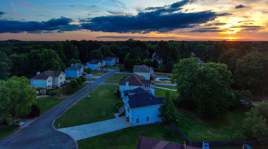 a breathtaking aerial shot of a sunset over Powder Springs Georgia with miles of vast green trees and homes with powerful clouds