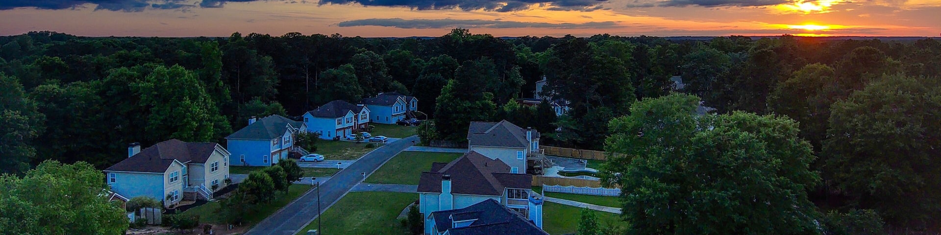 a breathtaking aerial shot of a sunset over Powder Springs Georgia with miles of vast green trees and homes with powerful clouds