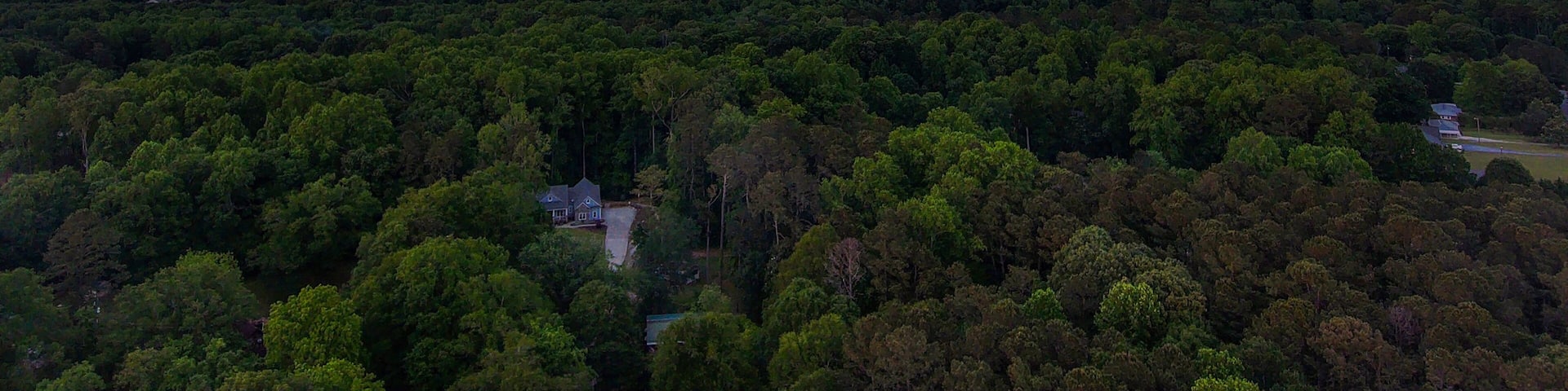 a breathtaking aerial panoramic shot of a sunset over Powder Springs Georgia with miles of vast green trees and homes with powerful clouds