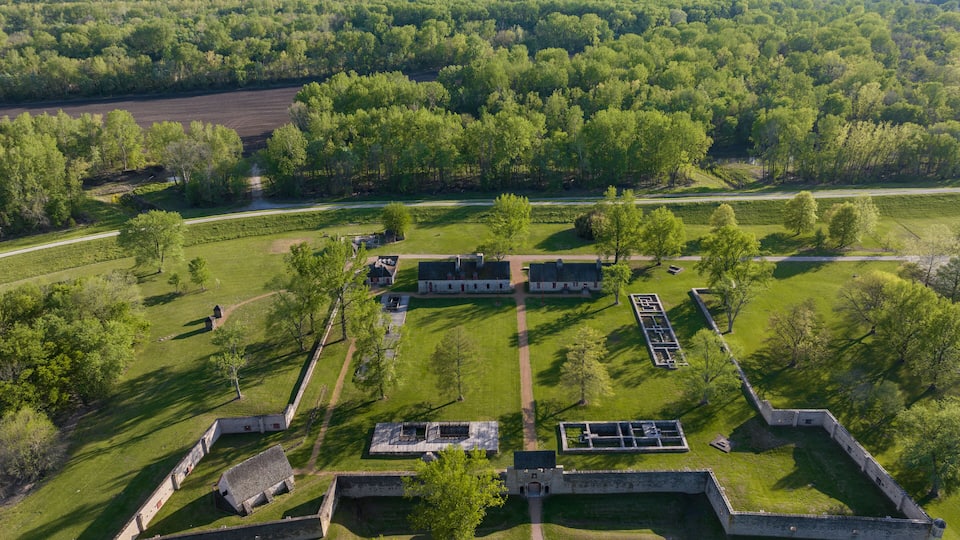 An aerial view of a historic fort with multiple buildings and a surrounding green landscape.