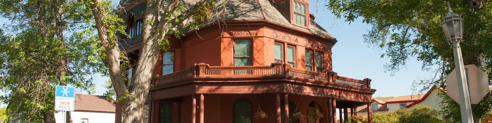 A historic red building with a large porch and a tower.