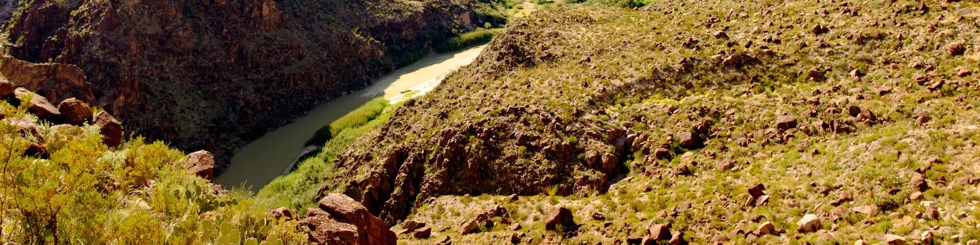 A canyon with a river winding through it, surrounded by rugged mountains.