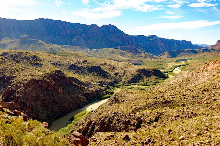 A canyon with a river winding through it, surrounded by rugged mountains.