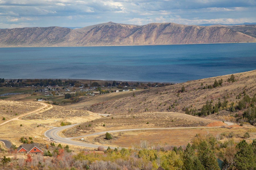 Un paisaje montañoso con un lago, carreteras serpenteantes y casas dispersas.