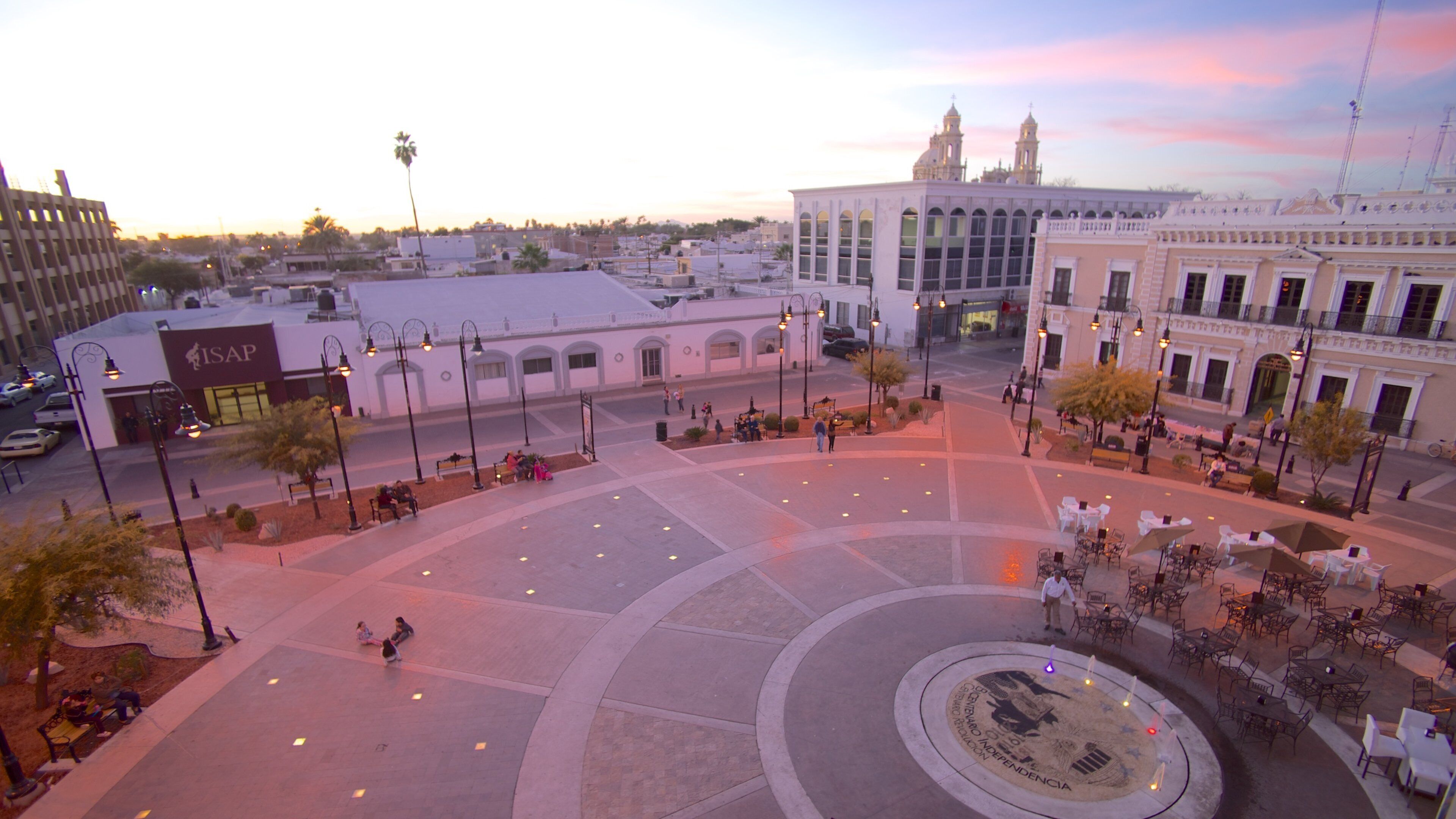 A plaza with a circular fountain, benches, and outdoor seating areas.