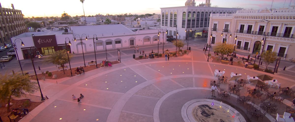 A plaza with a circular fountain, benches, and outdoor seating areas.