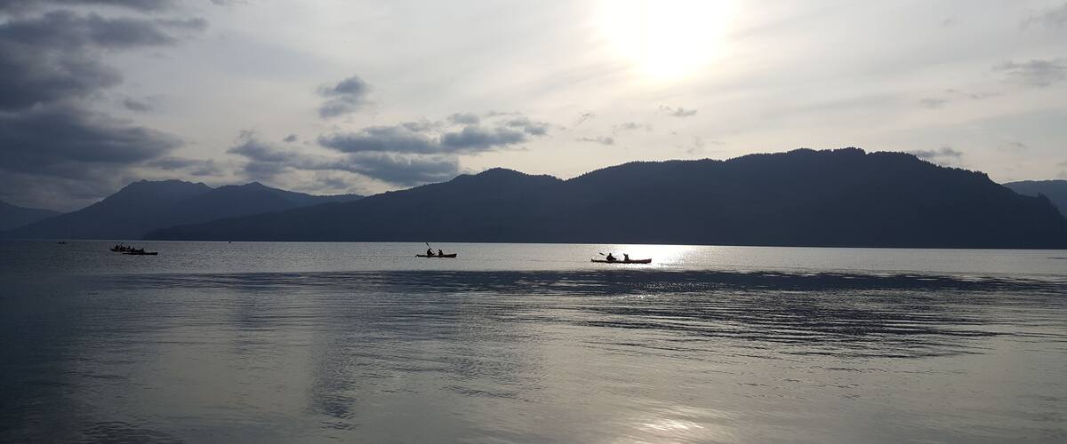 A calm lake with boats and mountains in the background.