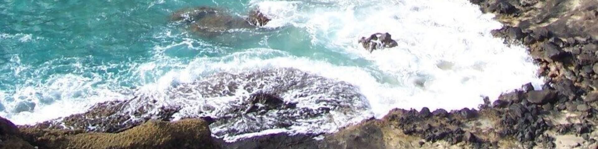 A rocky coastline with clear turquoise waters and a sandy beach.