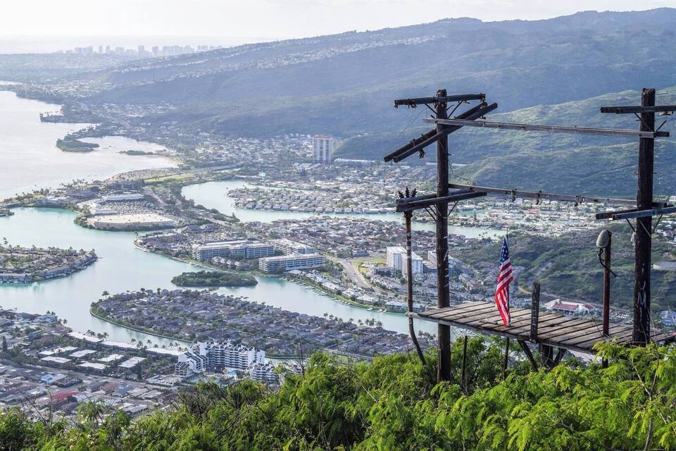 A coastal city with a river, buildings, and a flag on a wooden platform.