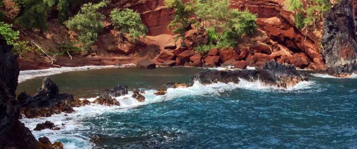 On the back side of Ka'uiki Hill in Hana, Red Sand (Kaihalulu) Beach is just a five minute hike, but steep drop offs and loose gravel from this cinder cone make it a treacherous trip. Not for the faint of heart or perpetually clumsy, but daring adventurers are rewarded with dramatic red cliffs and a cerulean blue cove providing a sheltered swimming area.