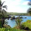 A tropical beach with clear blue water, rocky outcrops, and lush greenery.