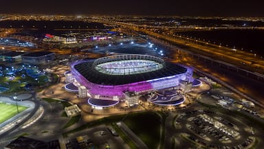 Un estadio grande con una estructura de techo distintiva, rodeado de calles y zonas de estacionamiento.