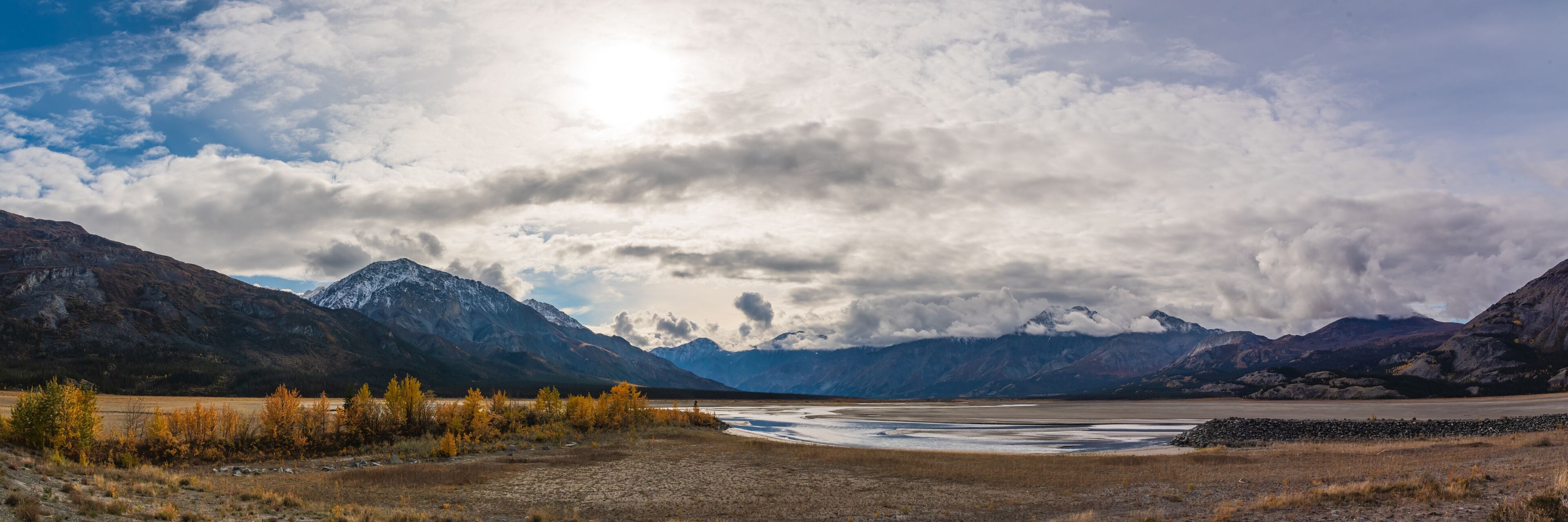 A mountainous landscape with a river and autumn-colored trees.