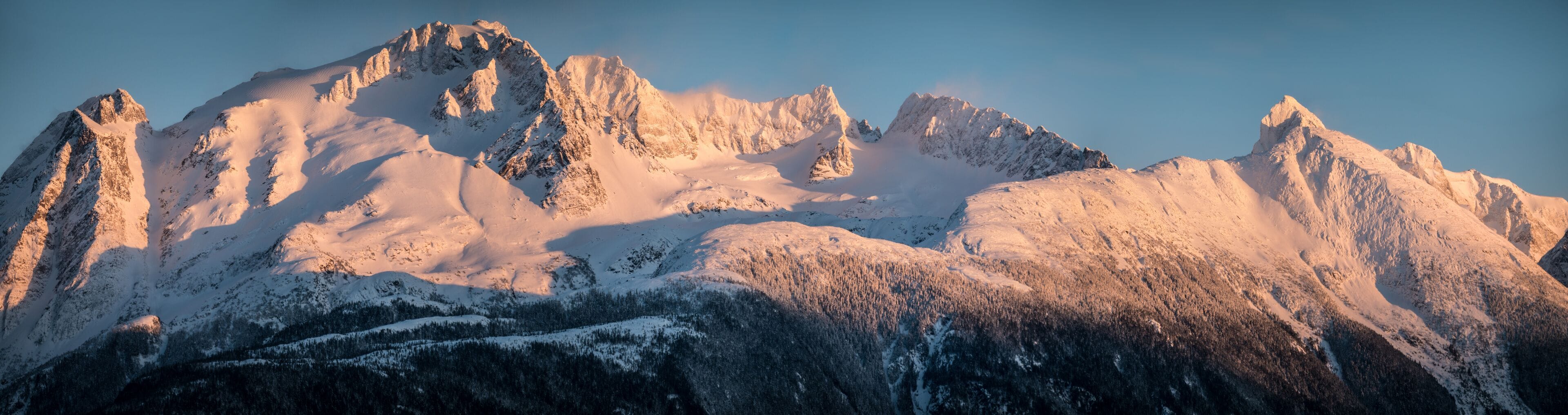 A snow-covered mountain range with sharp peaks and a clear sky.