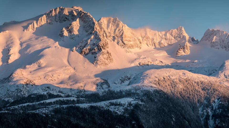 A snow-covered mountain range with sharp peaks and a clear sky.
