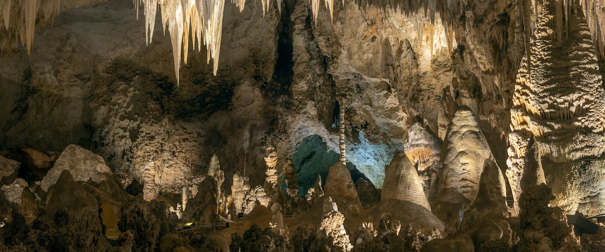 A cave with stalactites hanging from the ceiling and stalagmites rising from the ground.