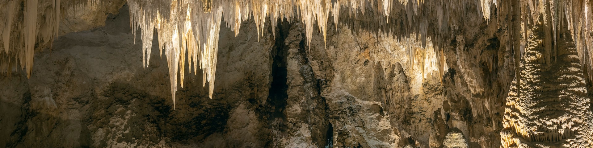 A cave with stalactites hanging from the ceiling and stalagmites rising from the ground.