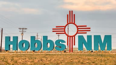 City entrance sign with large turquoise colored letters and large Zia sign