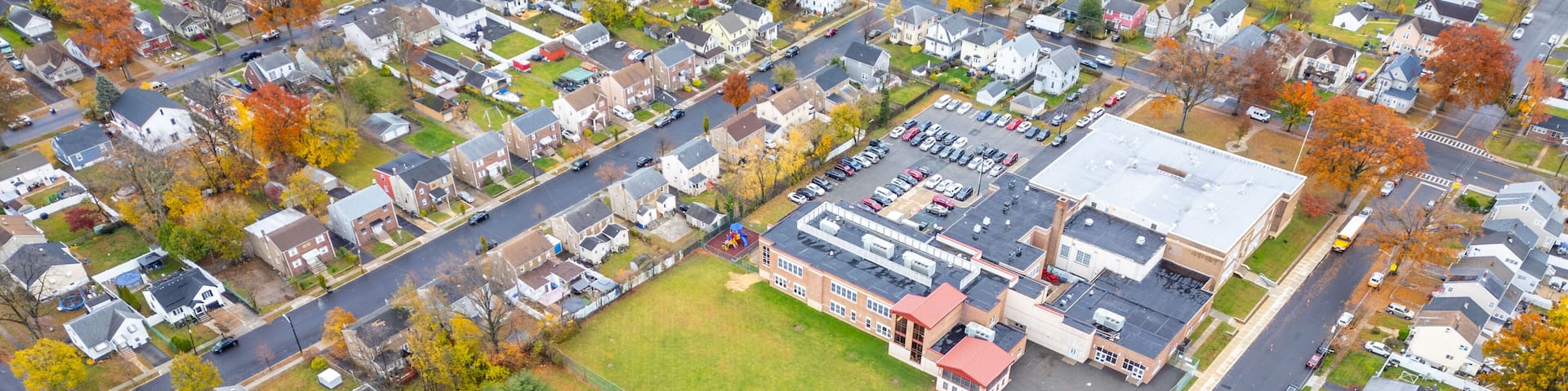 Aerial view of Rahway NJ near East Milton showing homes, winding streets, waterways, the Rahway River and nearby roads like Route 1 and Route 27 under an overcast sky. Scenic suburban landscape.
