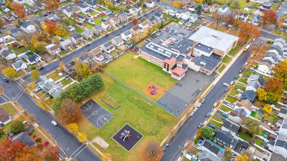 An aerial view of a residential area with houses, a school, and a playground.
