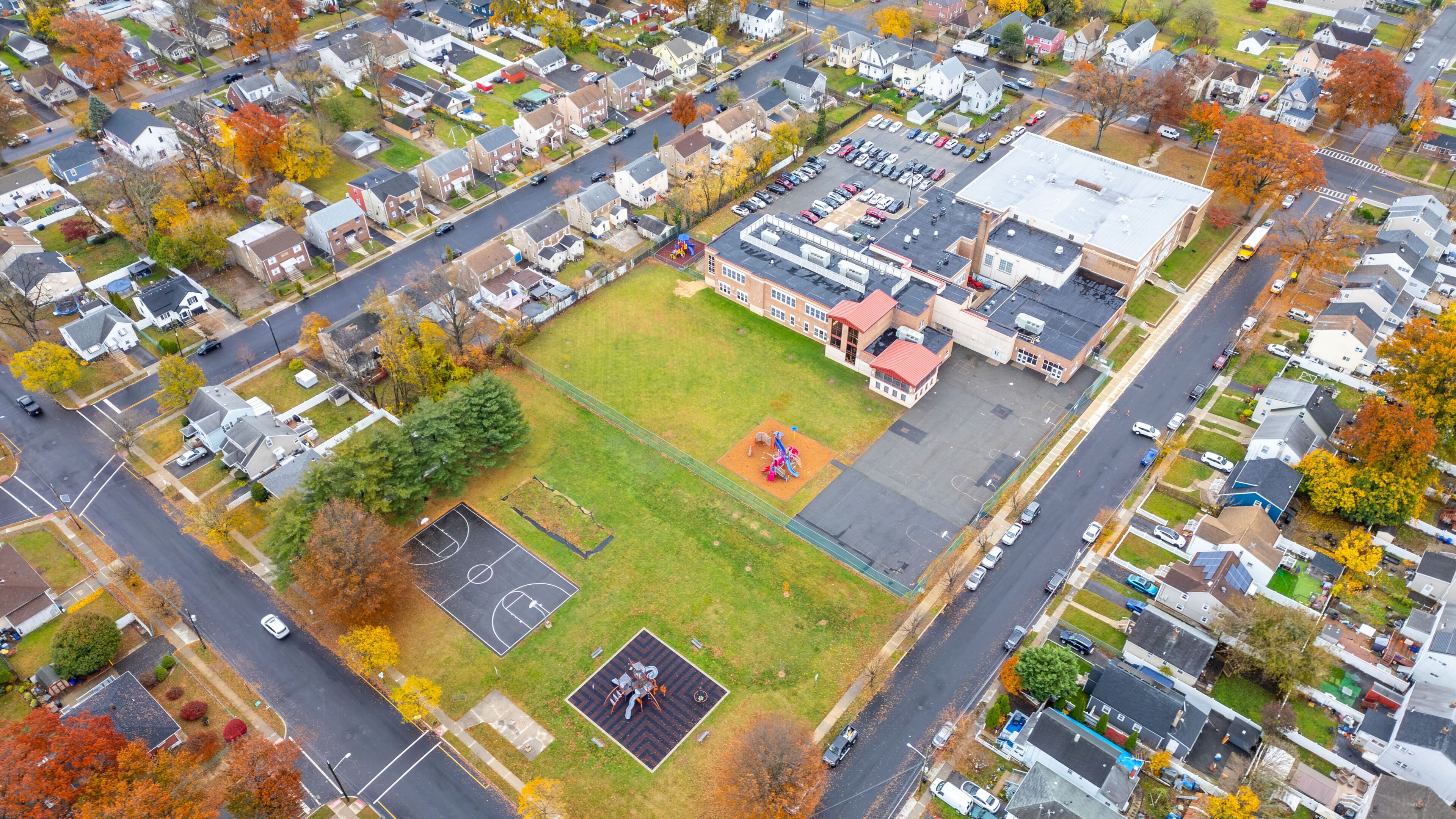 An aerial view of a residential area with houses, a school, and a playground.