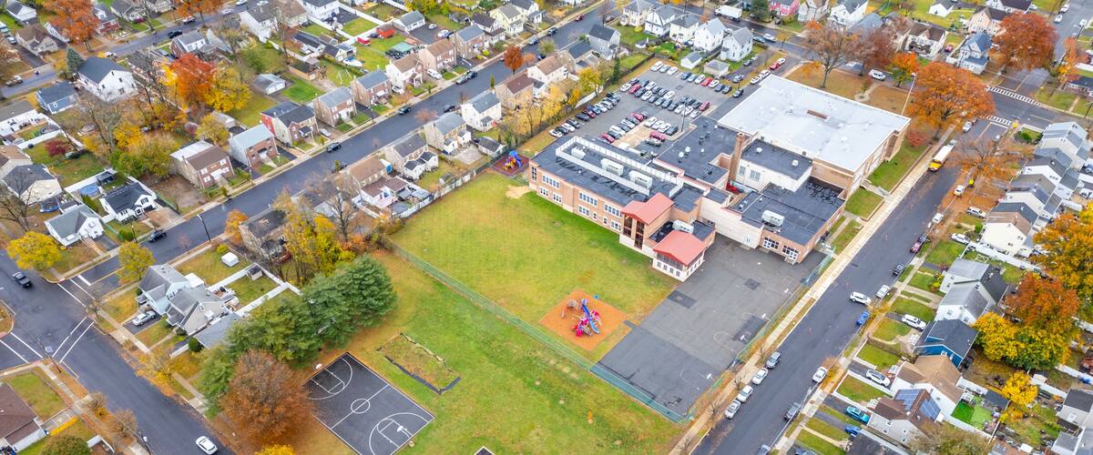 An aerial view of a residential area with houses, a school, and a playground.