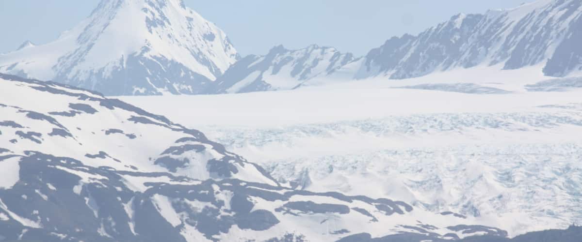 A snow-covered mountain range with rugged peaks and a valley below.