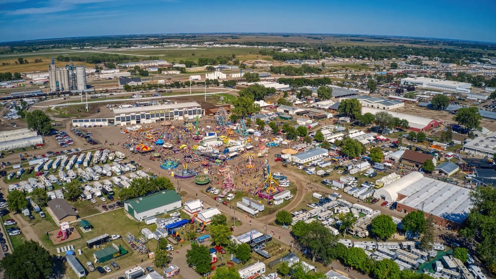 An aerial view of a fairground with a Ferris wheel, tents, and RVs.
