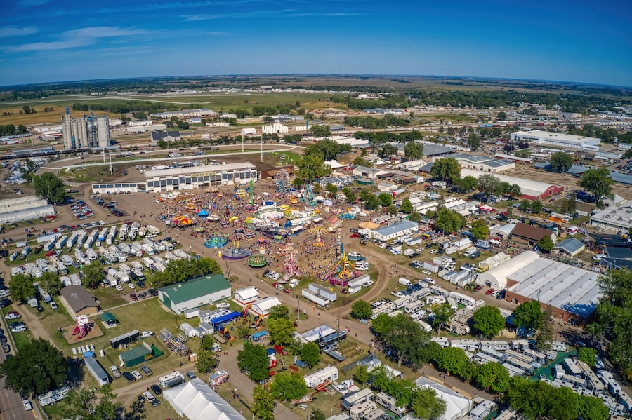 Vista aérea de uma feira com roda gigante, tendas e trailers.