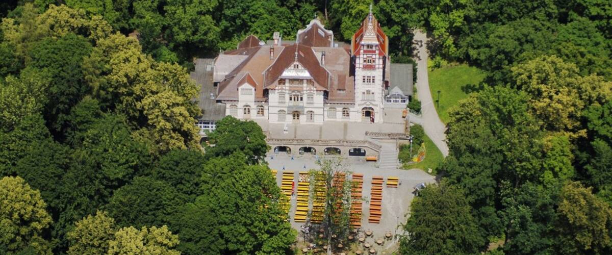 An aerial view of a historic castle surrounded by dense forest.