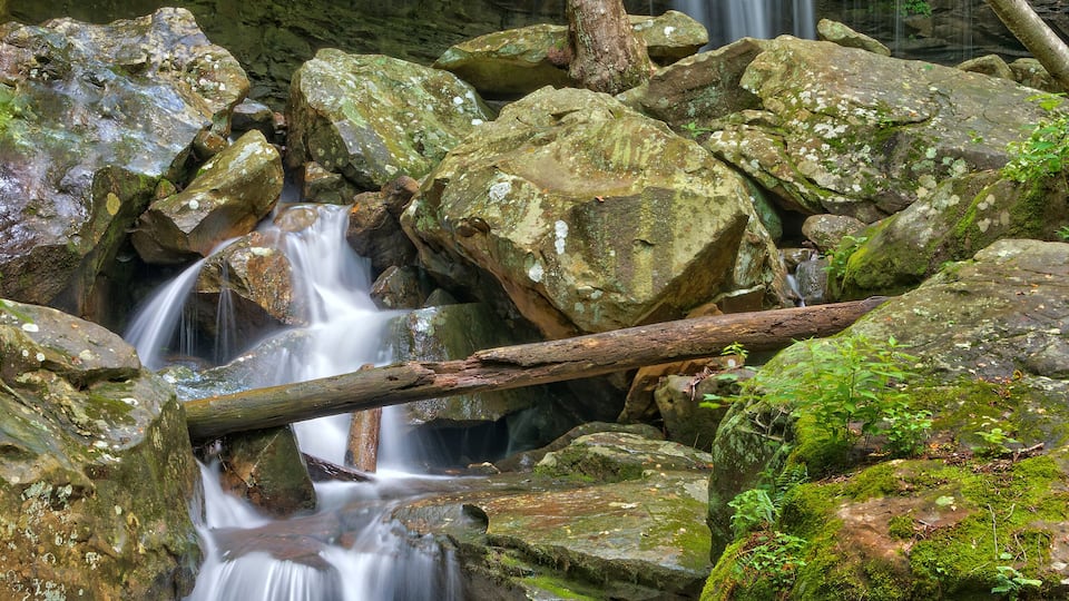 A waterfall cascading over rocks in a forested area.