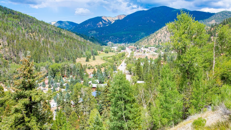 A valley with a small town nestled among dense forests and mountains.