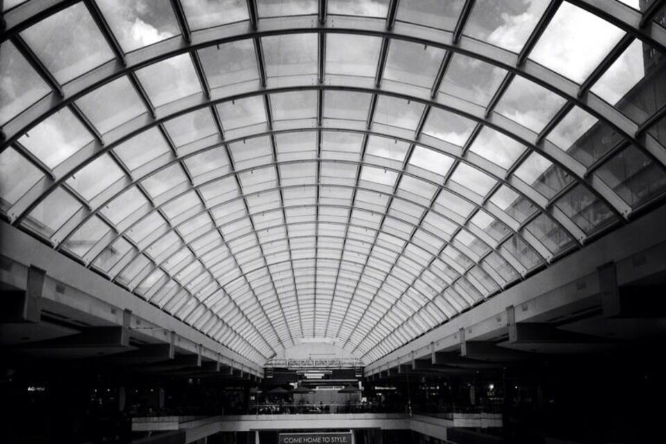 A large, modern shopping mall with a glass ceiling and multiple levels.