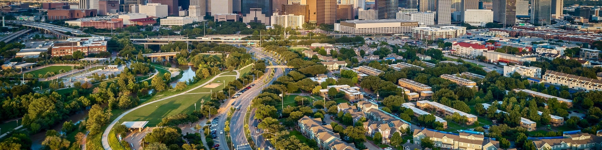 Un horizonte urbano con rascacielos modernos, un río y una zona residencial con casas y calles.