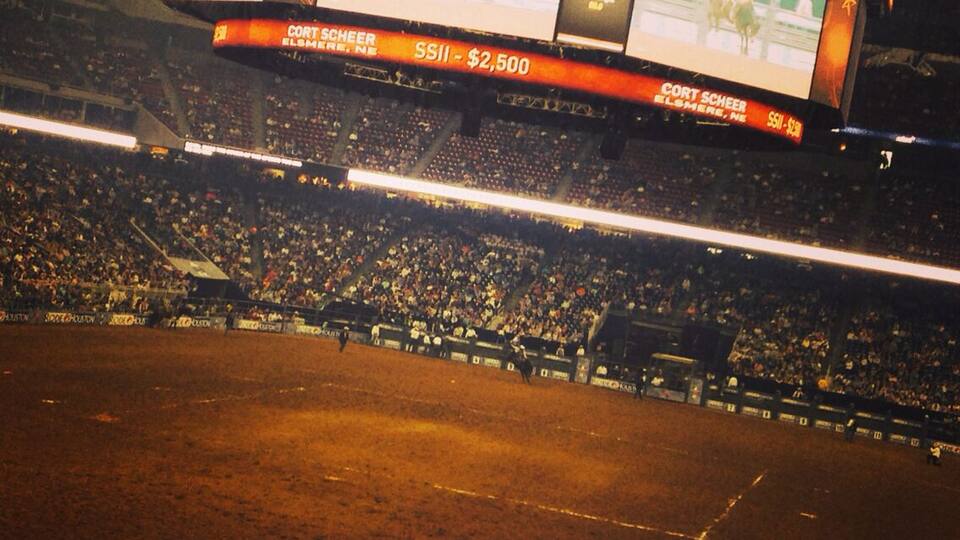 A rodeo arena with a dirt track and a large crowd.