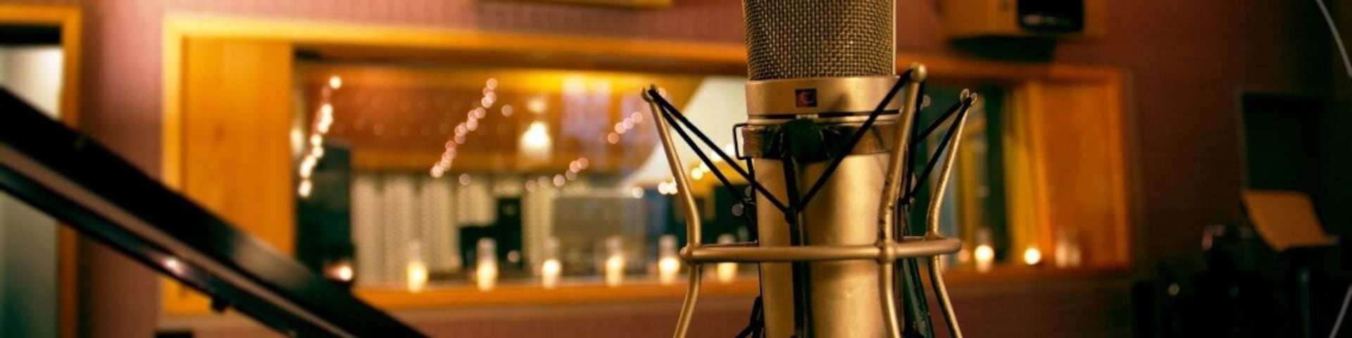 A microphone in a recording studio with a piano in the background.