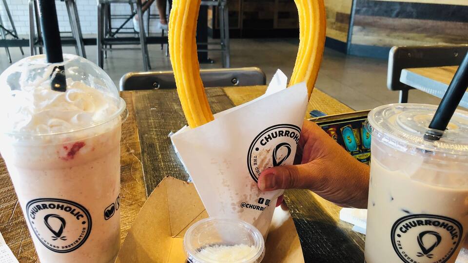 Ein Churro-Kegel, ein Milchshake und eine Bubble-Tea-Tasse auf einem Tisch.