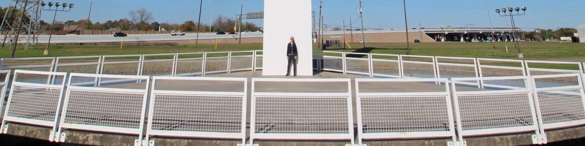 A large white cross monument on a platform with a person standing in front.