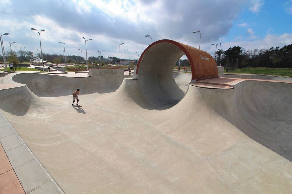 Una pista de skate con una rampa curva grande y una estructura roja.