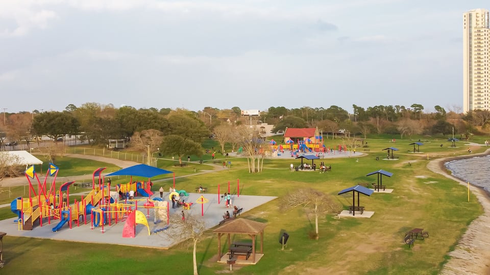 A park with playgrounds and picnic areas by a waterfront.