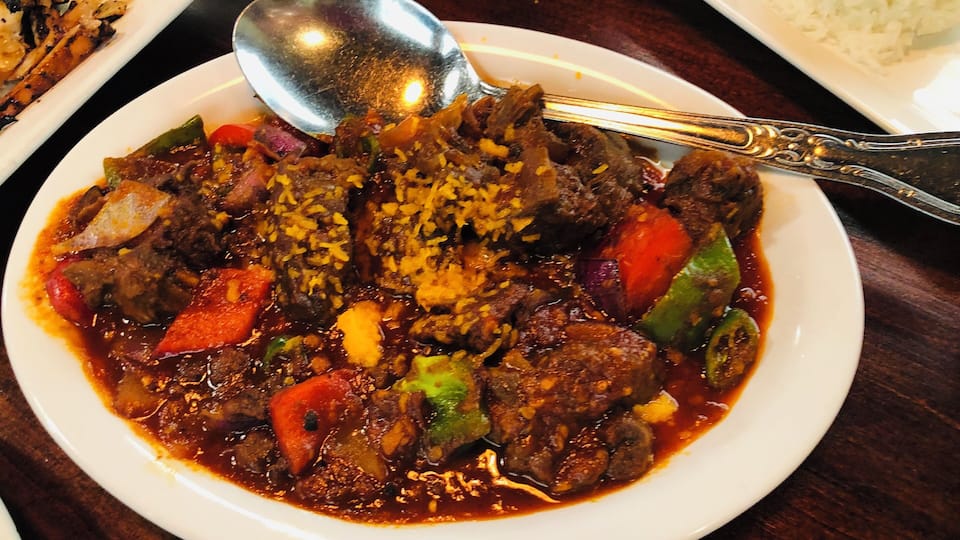 A plate of beef stew with rice, served on a wooden table.