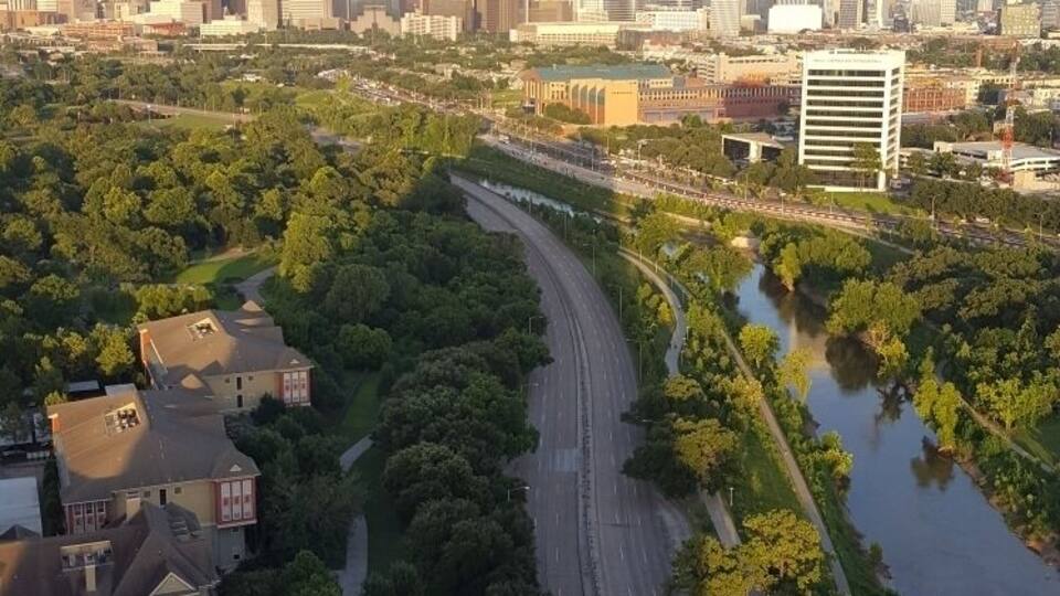 A cityscape with a river, green park, and modern buildings.