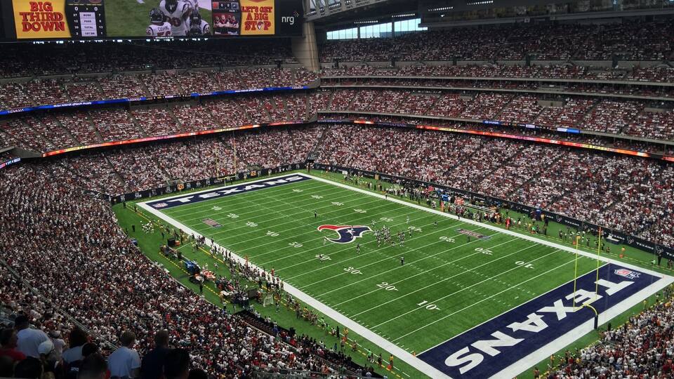 A football stadium with a large crowd, a scoreboard, and the Texas Longhorns logo on the field.