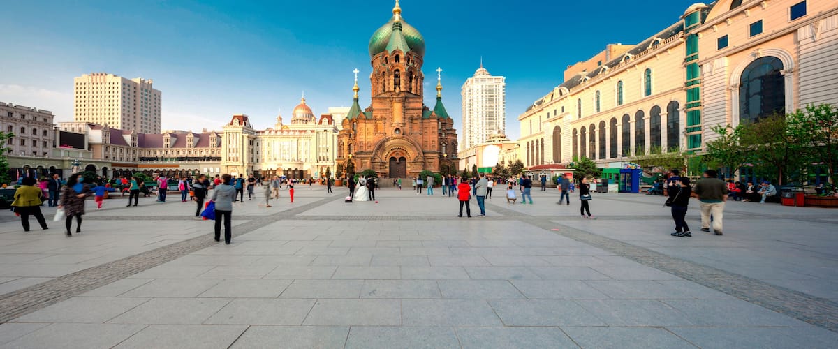 A large open square with a historic church in the center, surrounded by modern buildings.