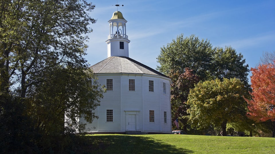 A white church with a bell tower and a green lawn.