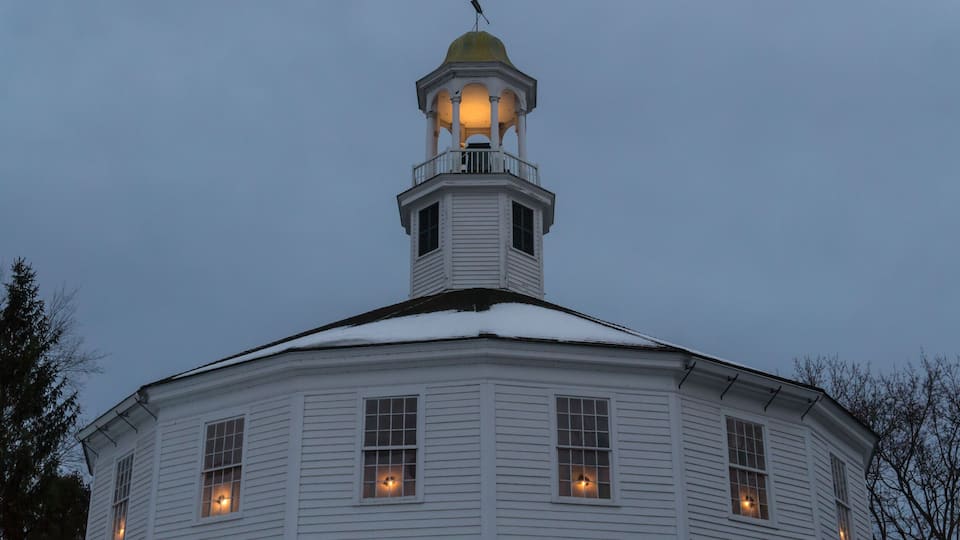 A white building with a bell tower and a snow-covered roof.