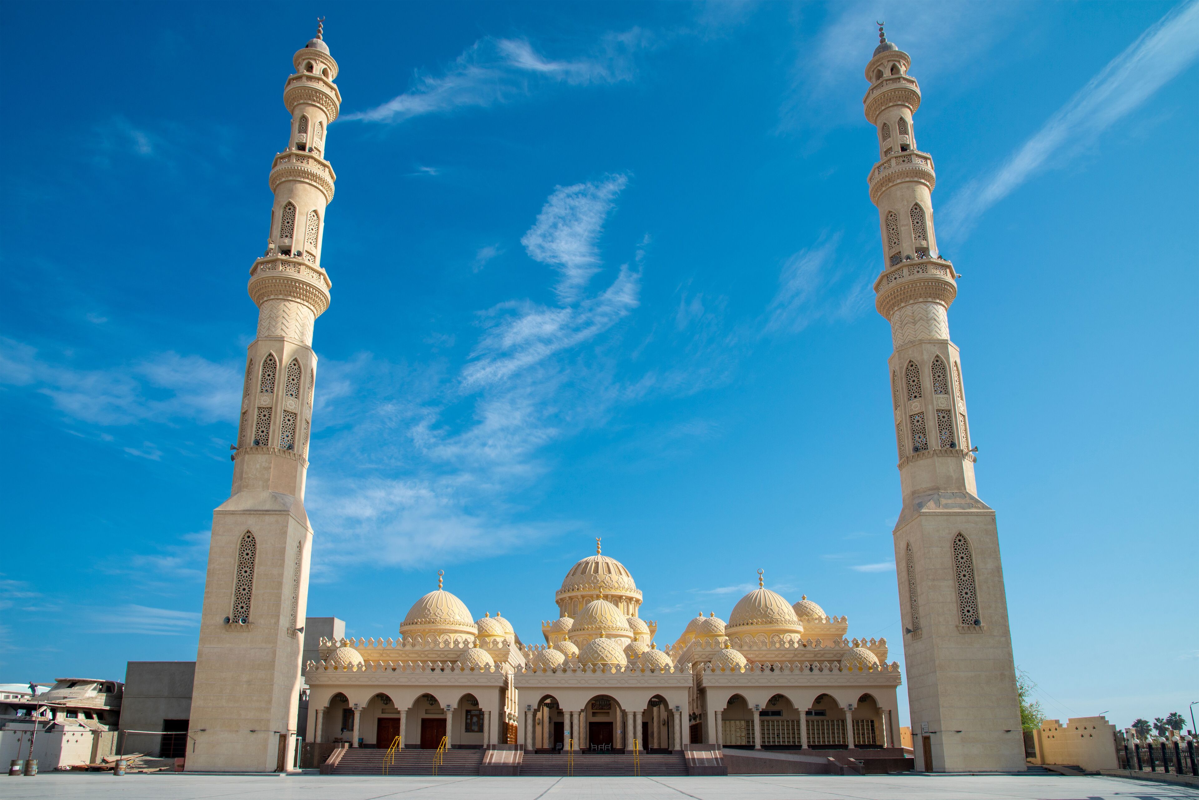 A mosque with two tall minarets, multiple domes, and a large courtyard.