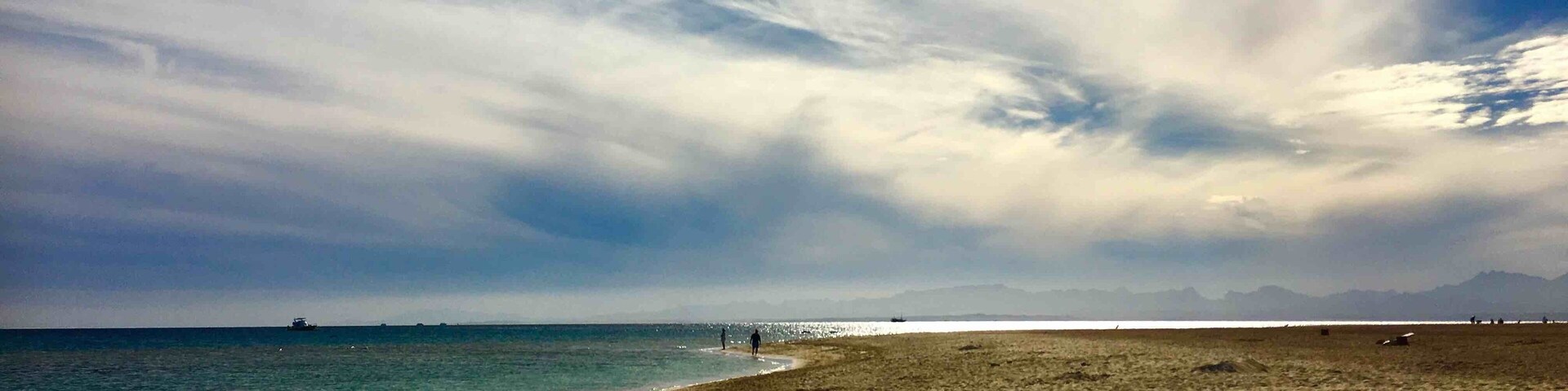 A beach with a clear sky and distant mountains.