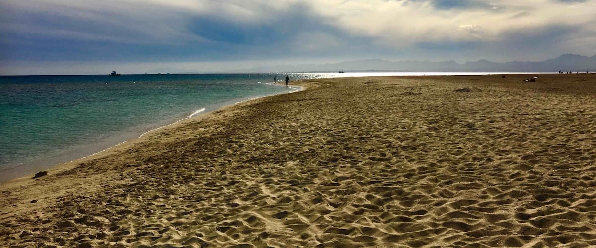A beach with a clear sky and distant mountains.